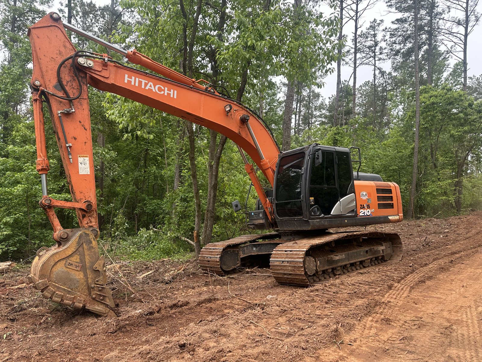 Excavator clearing wooded land